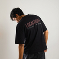 Person wearing a black t-shirt with 'LOCALHOST' text on the back, standing against a plain background.